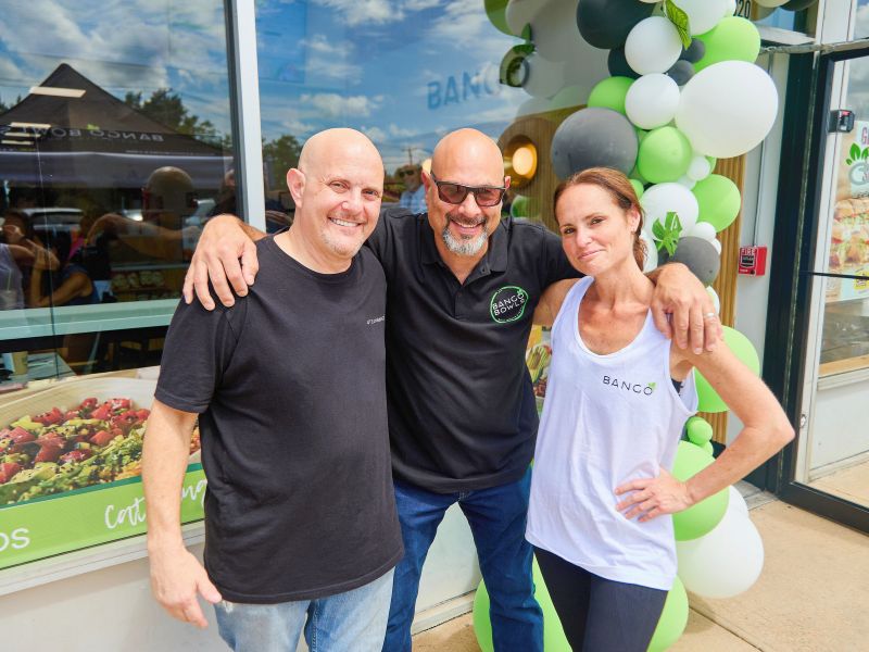 Bango Bowls franchisees celebrating at a grand opening with green and white balloons